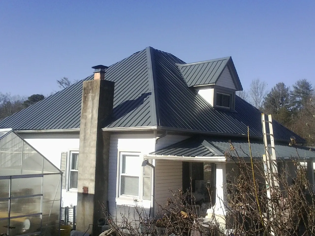 Dark blue standing seam metal roof on a white farmhouse with dormer — Slate & Tile Roof Repair by Roofing Brothers in Collingswood