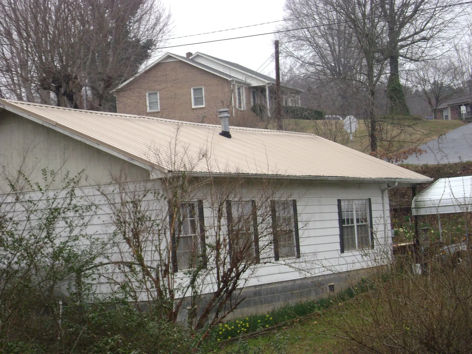 Tan metal roof on a white sided house set into a hillside — Commercial Roofing by Roofing Brothers in Collingswood