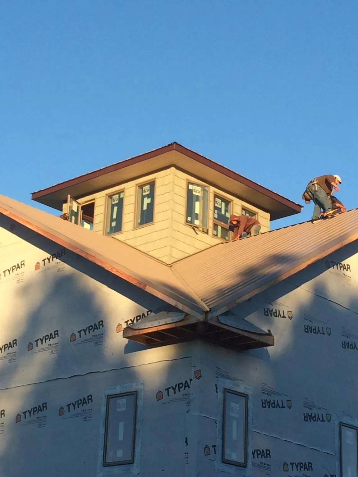 Roofers working around a rooftop cupola on a new metal roof at sunset — Roof Waterproofing in Collingswood by Roofing Brothers